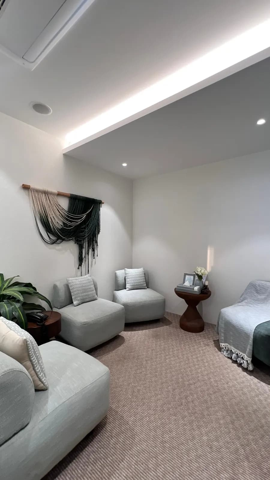A quiet counselling room at Mindsight Clinic, Boat Club Road, Pune, with soft grey seating and a woven wall hanging