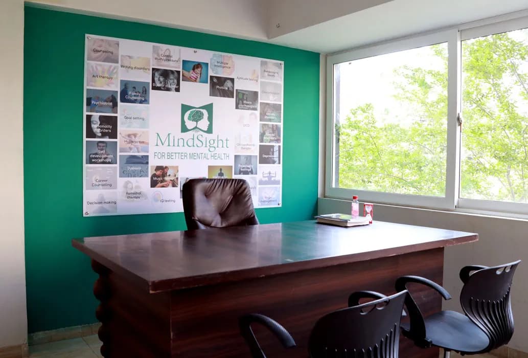 A consultation room at Mindsight Clinic, Malad West, Mumbai, with a desk in front of a green wall and a window