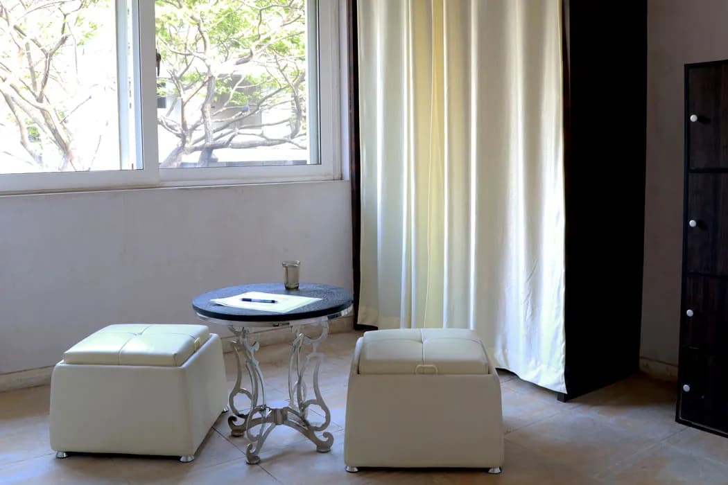 A quiet corner at Mindsight Clinic, Malad West, Mumbai, with two white ottomans and a small table by the window